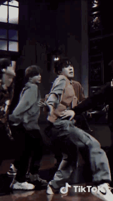 a group of people are dancing in a room with tiktok written on the bottom right