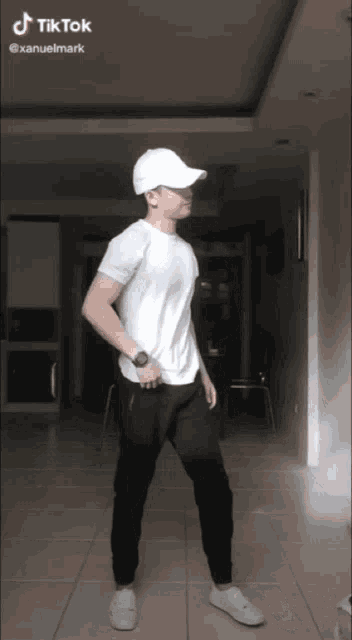 a man wearing a white hat and a white shirt is dancing in a room with a tik tok watermark
