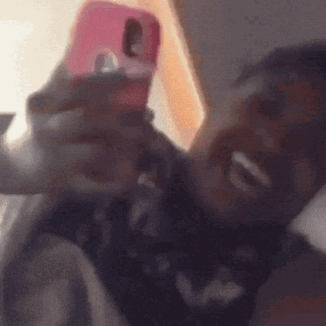a person is taking a selfie with a pink cell phone