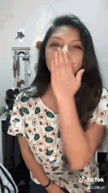 a woman is covering her mouth with her hand while wearing a polka dot shirt .