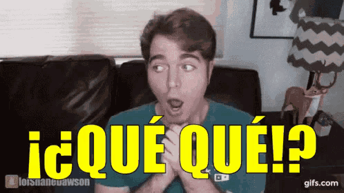 a man with a surprised look on his face is sitting on a couch with the words i que que written on the screen .