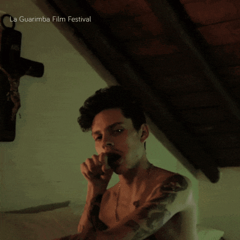 a man without a shirt is standing in front of a cross with the words la guarimba film festival below him