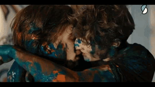 a man and a woman are kissing covered in blue paint