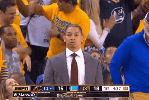 a man in a suit and tie stands in a crowd watching a basketball game