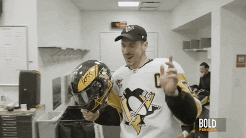 a man in a penguins jersey holds a helmet in his hand