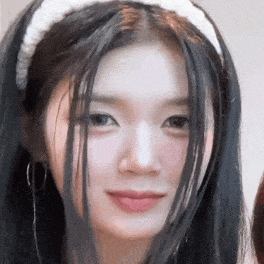 a close up of a woman with long black hair wearing a white headband .