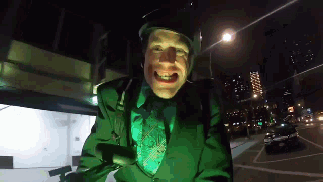 a man in a green suit and tie is smiling