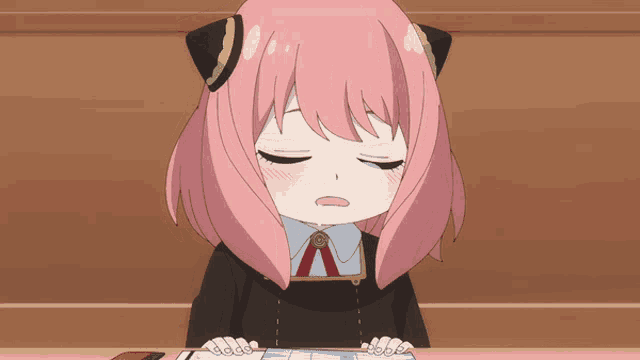 a girl with pink hair is sitting at a desk
