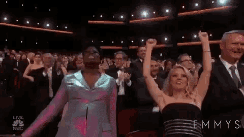 a man in a pink suit is dancing in front of a crowd of people at an emmy awards show .