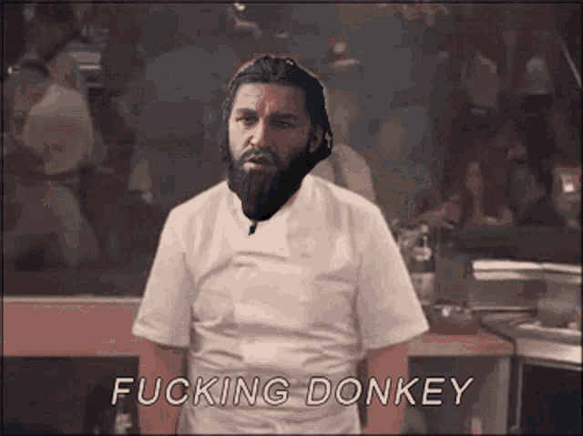 a man with a beard is standing in a kitchen with the words " fucking donkey " below him