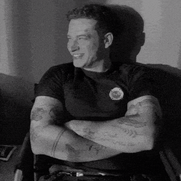 a black and white photo of a man with tattoos on his arms and chest