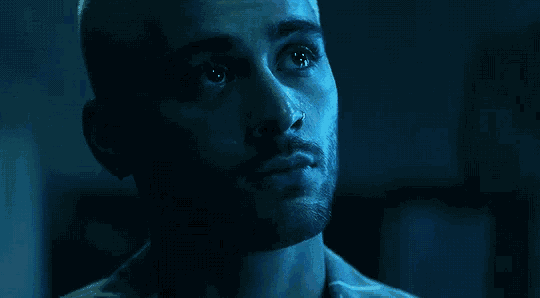 a close up of a man 's face with a nose ring in the dark .