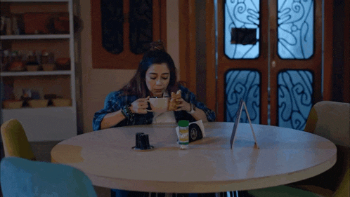 a woman sits at a table with a cup of coffee