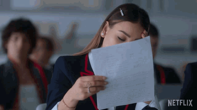 a woman is reading a piece of paper with a netflix logo behind her