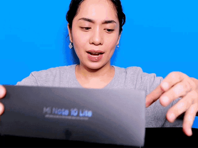 a woman opens a box that says mi note 10 lite on it