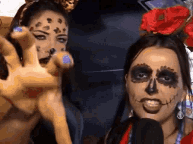 a woman with a leopard print on her face is standing next to another woman with a skeleton face painted on her face