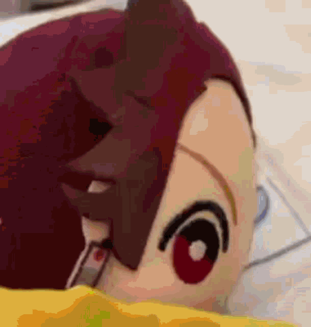 a close up of a stuffed animal with red eyes laying on a bed .