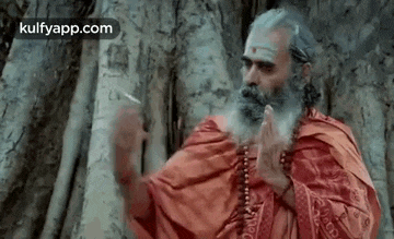 a man with a beard is praying and smoking a cigarette .