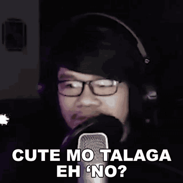 a man wearing glasses and headphones is talking into a microphone and saying `` cute mo talaga eh no '' .