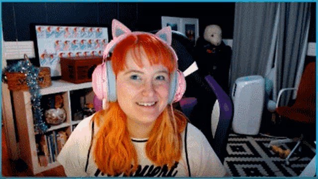 a woman with red hair wearing pink headphones and a shirt that says night