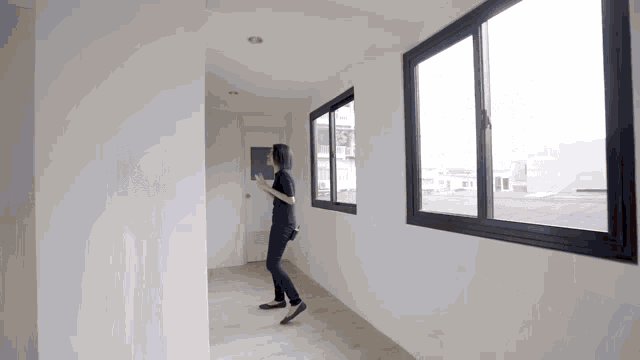 a woman is standing in a hallway looking out the window