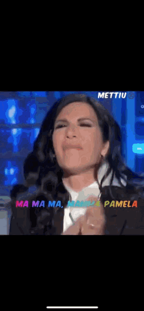 a woman applauds in front of a screen that says mettiu on it