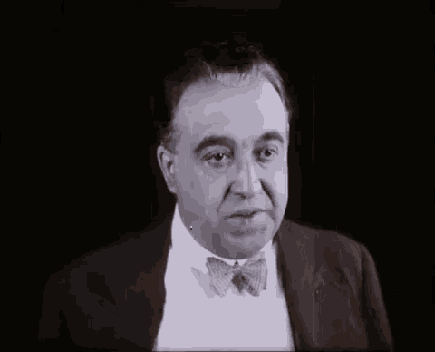 a black and white photo of a man in a suit and tie .