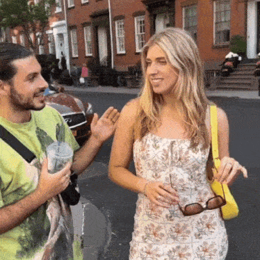 a man in a green shirt is talking to a woman in a white floral dress