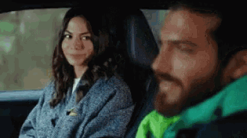 a man and a woman are sitting in the back seat of a car and smiling .