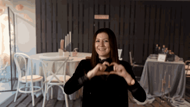 a woman making a heart shape with her hands in front of a sign that says " closed "