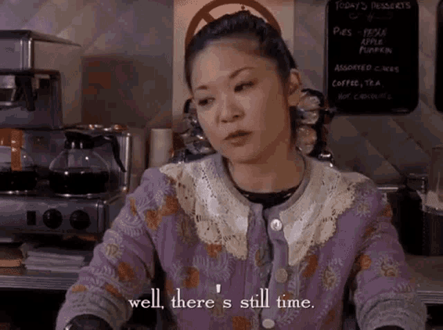 a woman in a purple sweater is sitting at a counter in a restaurant .