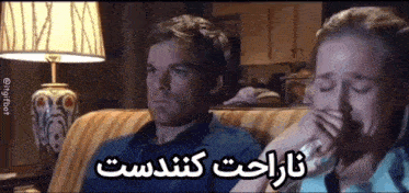 a man and a woman are sitting on a couch and the woman is crying while the man looks on .