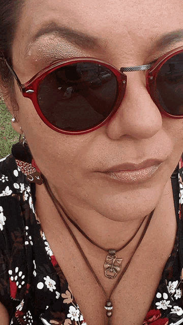 a woman wearing sunglasses and a necklace with a tiki face pendant