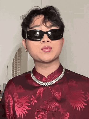 a man wearing a red shirt and sunglasses is making a face .