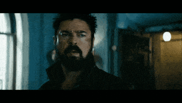 a man with a beard is standing in a dark hallway