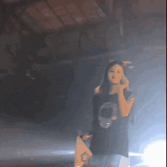 a woman in a black shirt is singing into a microphone on stage
