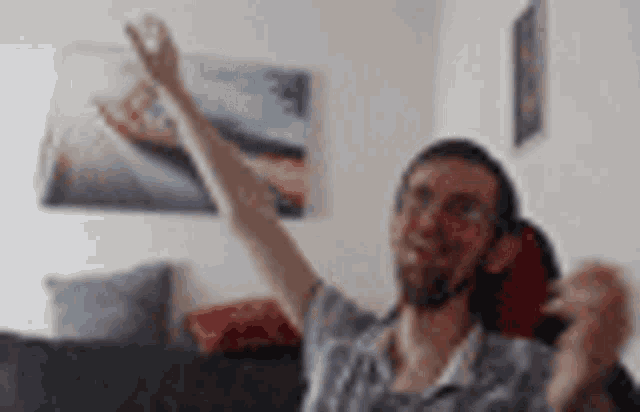 a man is sitting on a couch with his arms in the air while wearing headphones .