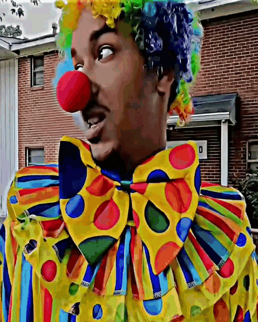 a man is dressed as a clown with a red nose