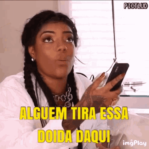 a woman is holding a cell phone with the words alguem tira essa doida daqui above her