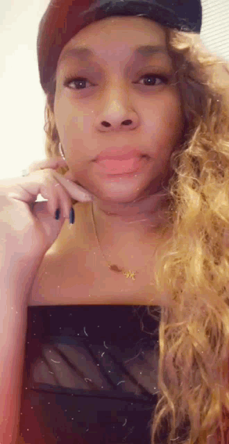 a woman wearing a hat and a necklace is making a face .