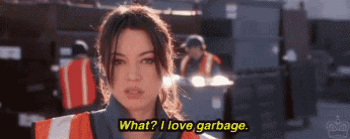 a woman wearing a safety vest is talking about garbage .
