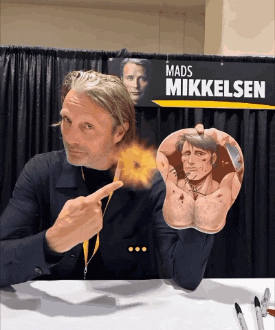 a mads mikkelsen sign hangs above a man 's arm