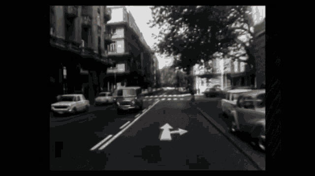 a black and white photo of a city street with a van driving down it