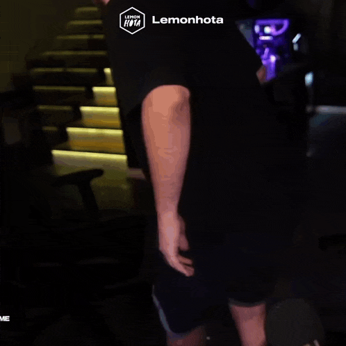a man in a black shirt is standing in front of stairs with a lemonhota logo on his shirt