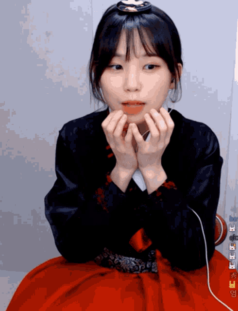 a girl with a crown on her head is making a heart shape with her hands
