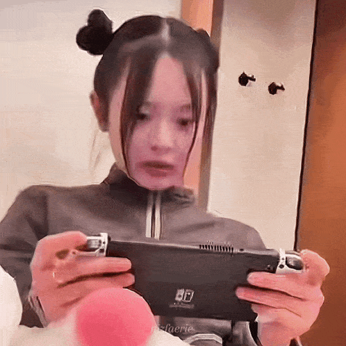a woman is holding a nintendo switch in her hands .