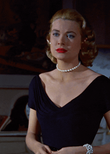 a woman wearing a pearl necklace and a black shirt