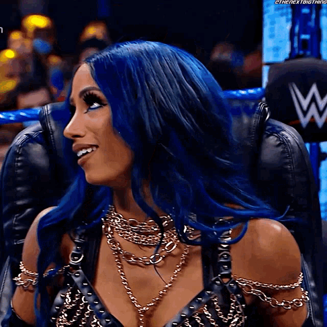 a woman with blue hair is sitting in a chair with a w on the back