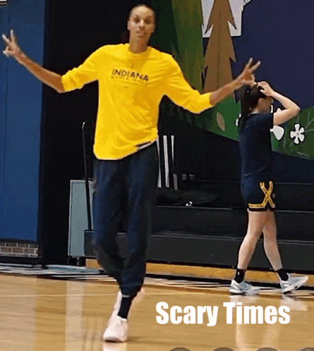 a woman wearing a yellow indiana shirt dancing on a basketball court