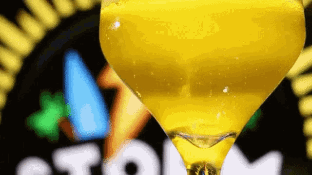 a close up of a yellow drink in a martini glass with the word storm in the background